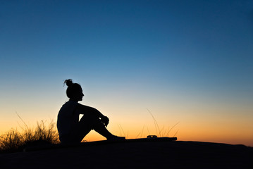 Obraz na płótnie Canvas Sylwetka kobiety siedzi słońca