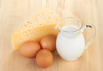 Big piece of cheese, glass jug with milk