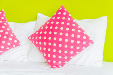 Colorful polka pillow on white bed