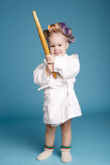 Fototapeta premium young housewife with rolling pin on blue background
