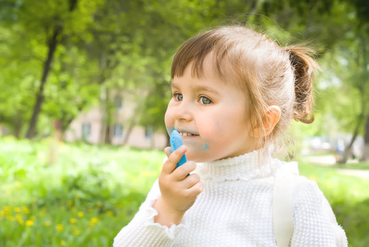 Cute little hellion girl with blue chalk outdoors