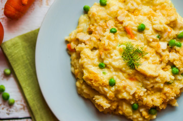 Rice with vegetables and chicken on white wooden background