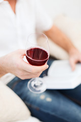 male hand holdind book and glass of red wine
