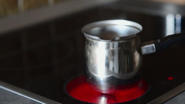 Coffee pot on cooking plate with boiling water in