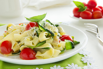 Pasta tagliatelle with zucchini and tomatoes.
