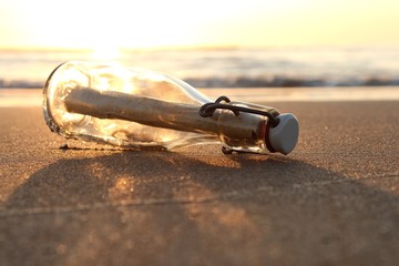 Flaschenpost am Strand bei Sonnenuntergang