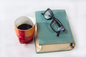 Glasses, a book and a cup of coffee on a white background