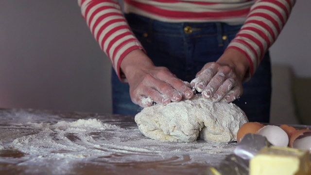 Female hand sprinkling flour on dough