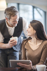 two young people watching a digital tablet in a cafe