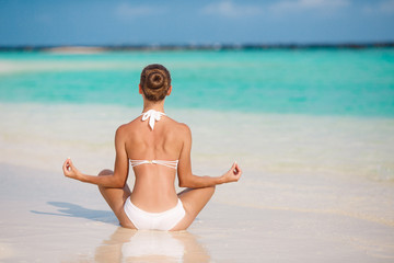 Fototapeta na wymiar Portrait of a young woman doing yoga on a tropical beach