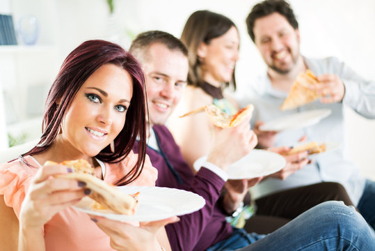 Group of happy friends sitting and eating pizza.