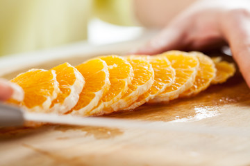 Female hands Cutting Orange in a kitchen.