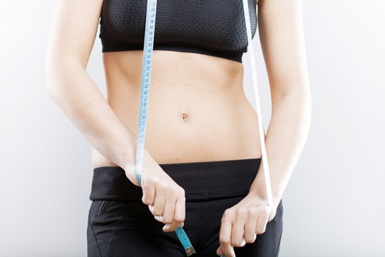 Woman belly and measuring tape, weight loss concept