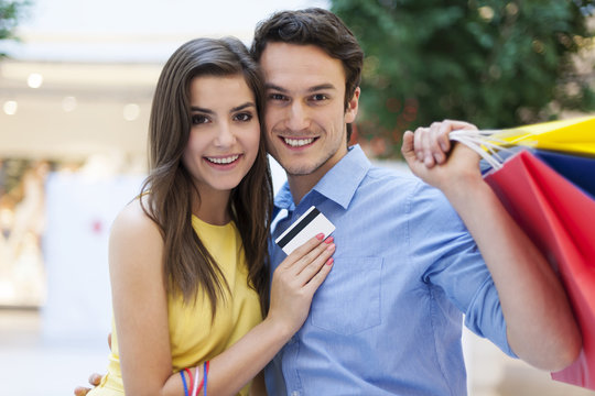 Portrait of smiling couple with credit card and shopping bags
