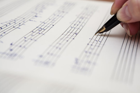 Hand With Pen And Music Sheet