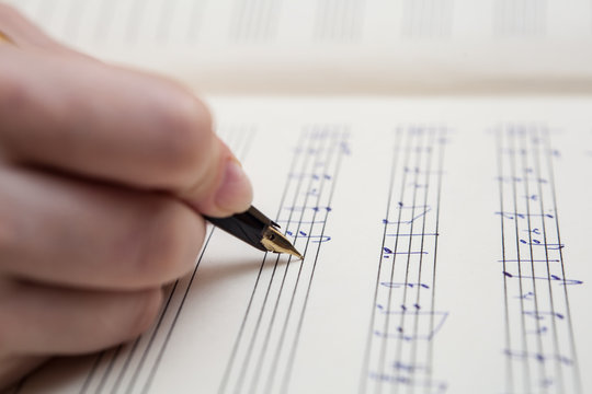 Hand with pen and music sheet