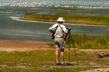 Tourist observing birds and taking photos by the lake