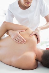 Obraz na płótnie Canvas Professional therapist giving shoulder massage to man