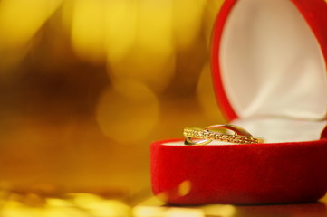 złoty pierścionek w czerwonym pudełku na złotym tle
