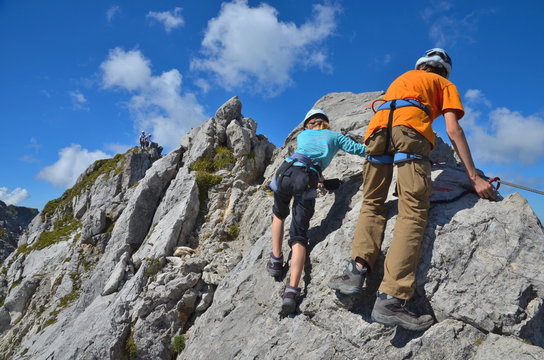 Kinder klettern am Fels im Klettersteig