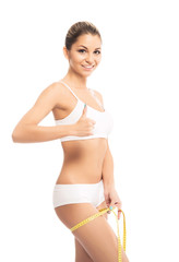 Fototapeta premium A fit and beautiful girl with a measuring tape isolated on white