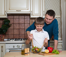 father and his son preparing a salad in the kitchen