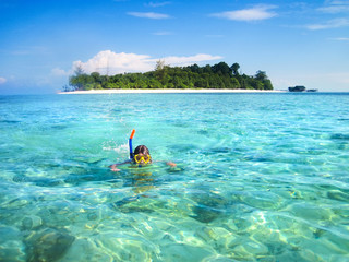 Little boy snorkeling next to a beautiful tropical island