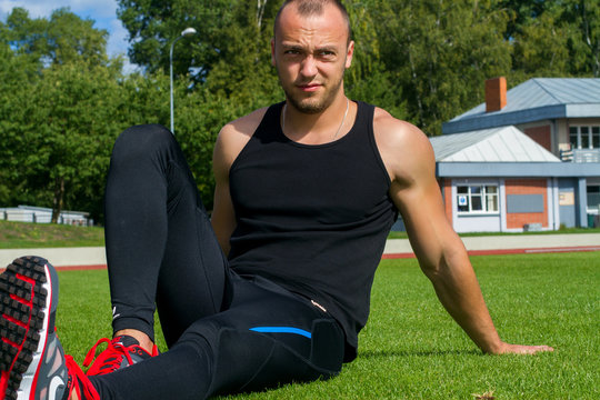 Image of muscle man sitting on stadium grass
