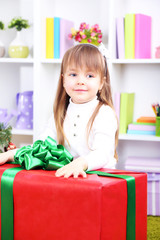 Little girl setting on  big present box in room