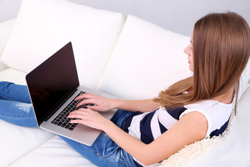 Young woman resting with laptop on sofa at home