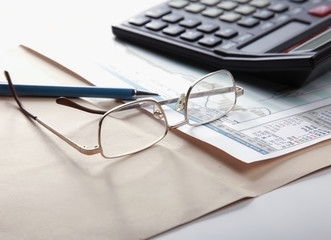 Calculator , folder with paper, pen and glasses.