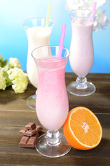 Milk shakes with fruits on table on light blue background