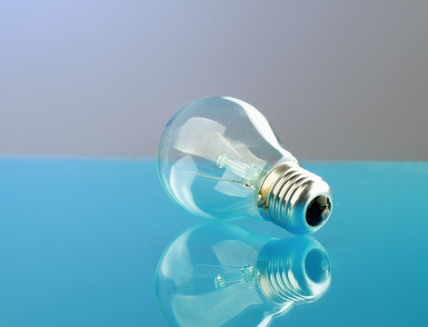 Light bulb isolated on blue glossy background.