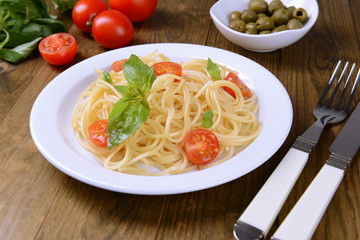 Delicious spaghetti with tomatoes on plate on table close-up