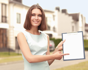 Female architect standing with folder near house