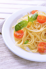 Delicious spaghetti with tomatoes on plate on table close-up