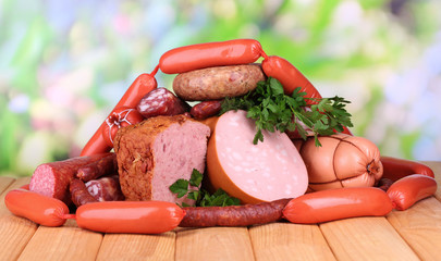 Lot of different sausages on wooden table on natural background