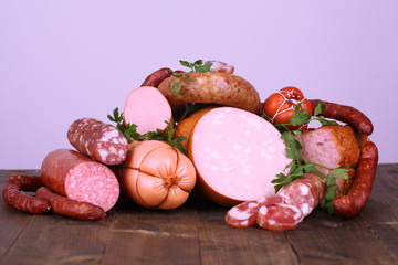 Lot of different sausages on wooden table on grey background