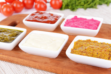 Various sauces on chopping board on table close-up
