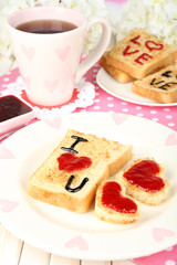 Delicious toast with jam and cup of tea on table close-up