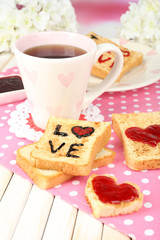 Delicious toast with jam and cup of tea on table close-up