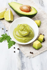 Fresh guacamole in bowl on wooden table