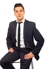 Smiling young handsome businessman at a suit sitting on chair