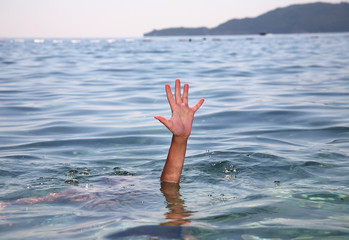 Help concept of a hand stretching out of the water in the sea