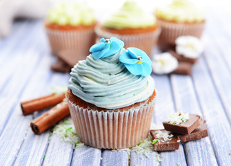 Tasty cupcakes with butter cream, on color wooden background
