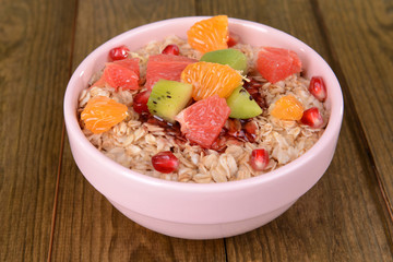 Delicious oatmeal with fruit in bowl on table close-up