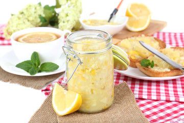 Tasty lemon jam with cup of tea on table close-up