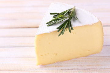 Tasty Camembert cheese with rosemary, on wooden table