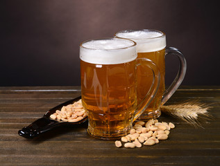 Glasses of beer with snack on table on dark background
