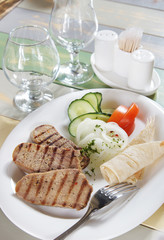 Fried pieces of meat with vegetables on the served table